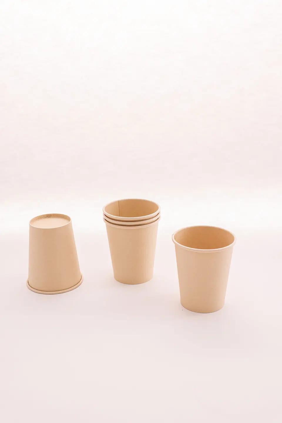 Three plain kraft paper cups, one turned over and one a stack